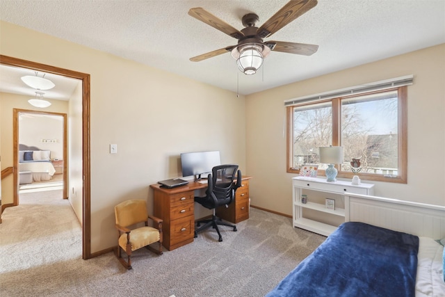 carpeted home office featuring a ceiling fan, baseboards, and a textured ceiling