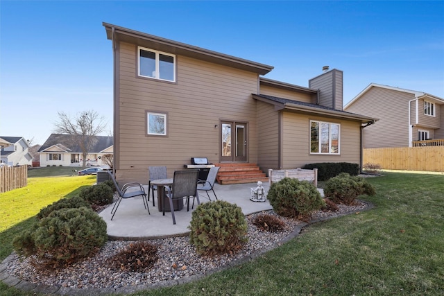 rear view of property with a patio, fence, a lawn, and a chimney