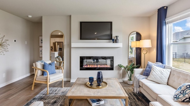 living room featuring wood finished floors, a glass covered fireplace, and baseboards