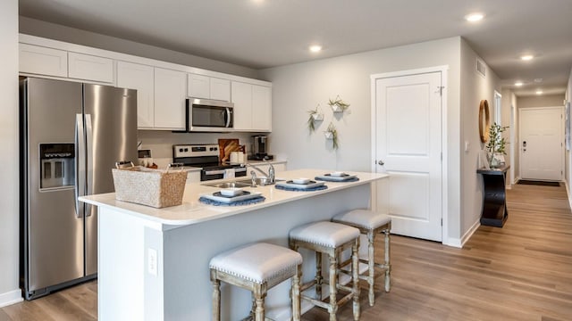 kitchen featuring light wood-type flooring, appliances with stainless steel finishes, white cabinets, and recessed lighting