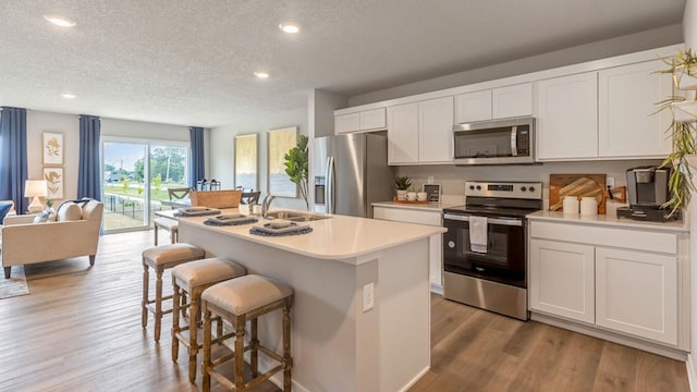 kitchen featuring light countertops, appliances with stainless steel finishes, light wood-type flooring, and a kitchen bar