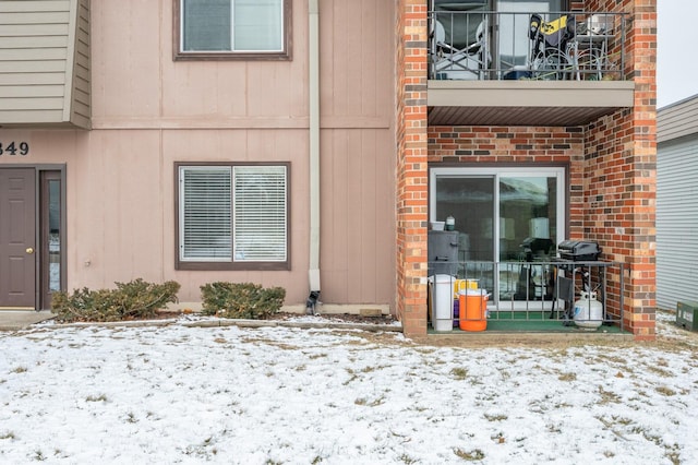 snow covered property entrance featuring a balcony