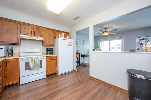 kitchen featuring under cabinet range hood, white appliances, brown cabinetry, and a ceiling fan