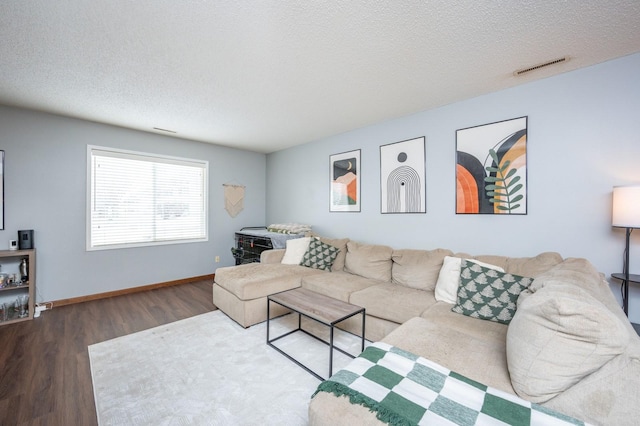 living area with baseboards, wood finished floors, visible vents, and a textured ceiling