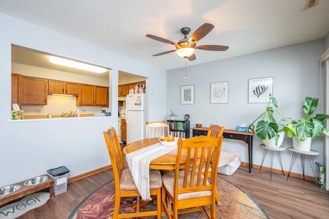 dining area featuring ceiling fan, baseboards, a textured ceiling, and wood finished floors