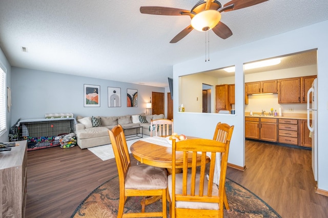 dining area with ceiling fan, visible vents, a textured ceiling, and dark wood finished floors