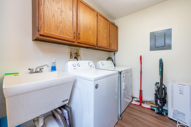 laundry area featuring a sink, electric panel, a textured ceiling, washing machine and dryer, and cabinet space