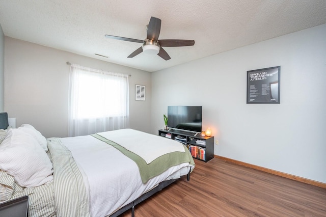 bedroom featuring a ceiling fan, visible vents, wood finished floors, baseboards, and a textured ceiling