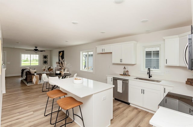 2503 Shaw St, Des Moines, IA 50317 - kitchen featuring stainless steel dishwasher, a sink, a kitchen island, light wood finished floors, and a breakfast bar area