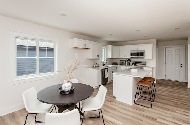 2503 Shaw St, Des Moines, IA 50317 - kitchen with stainless steel appliances, a sink, light countertops, white cabinetry, and light wood finished floors