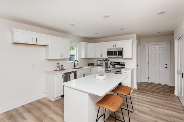 2503 Shaw St, Des Moines, IA 50317 - kitchen featuring appliances with stainless steel finishes, a sink, light wood-style floors, baseboards, and white cabinets