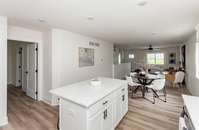 2503 Shaw St, Des Moines, IA 50317 - kitchen with light wood-type flooring, ceiling fan, a kitchen island, and light countertops