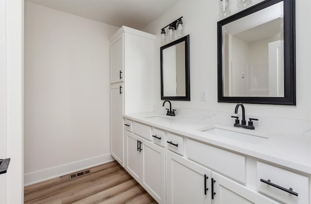 2503 Shaw St, Des Moines, IA 50317 - bathroom featuring double vanity, wood finished floors, and baseboards