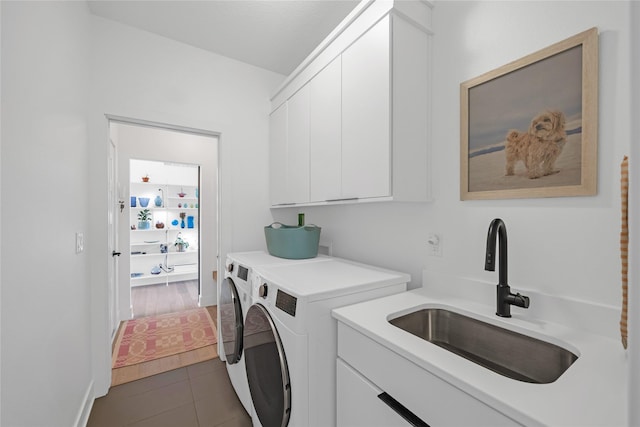 laundry area with cabinets, washing machine and dryer, dark tile patterned flooring, and sink