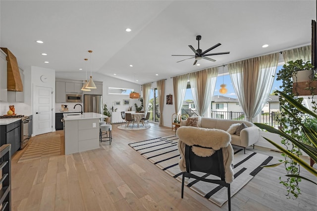 living room with plenty of natural light, light hardwood / wood-style floors, lofted ceiling, and ceiling fan