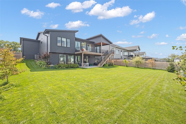 back of property with a yard, a balcony, and a patio