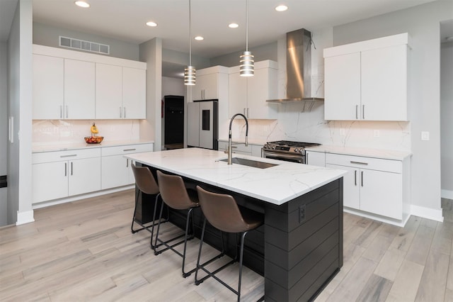 kitchen featuring wall chimney exhaust hood, white cabinetry, and appliances with stainless steel finishes