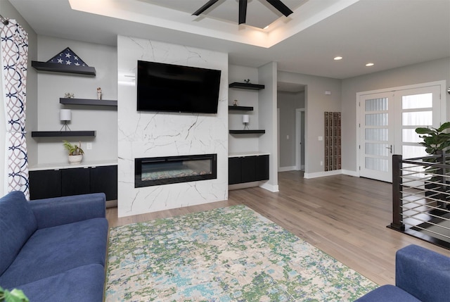 living room featuring a tray ceiling, a premium fireplace, and hardwood / wood-style floors