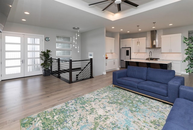 living room with ceiling fan, french doors, sink, and light hardwood / wood-style flooring