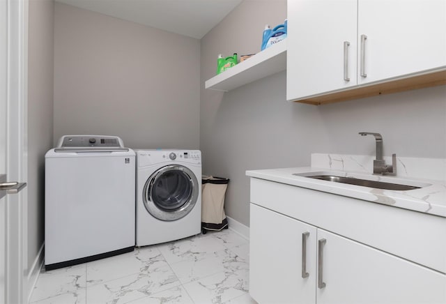 clothes washing area featuring washing machine and clothes dryer, cabinets, and sink