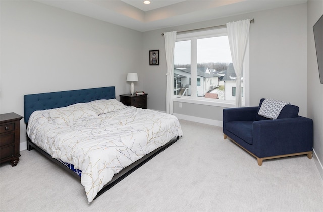 bedroom with a raised ceiling and light carpet