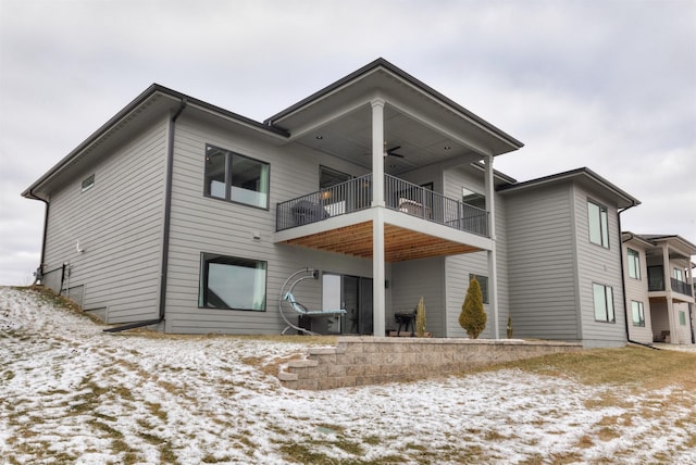 snow covered rear of property featuring a balcony