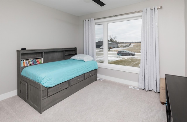 carpeted bedroom featuring multiple windows and ceiling fan