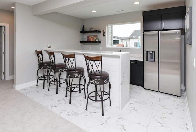 kitchen with a breakfast bar, stainless steel refrigerator with ice dispenser, kitchen peninsula, and beam ceiling