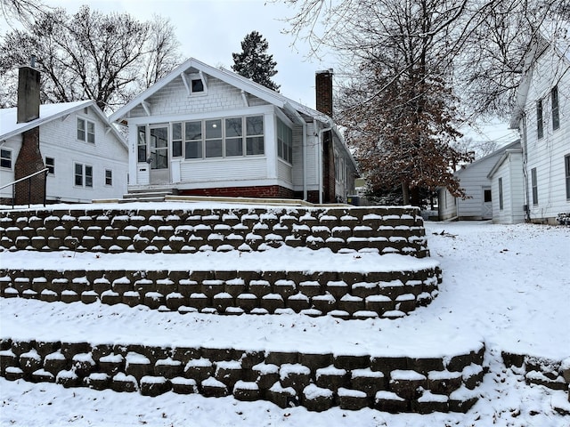 snow covered house featuring a sunroom