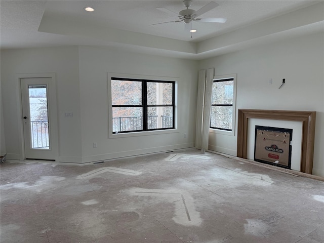 unfurnished living room with ceiling fan and a raised ceiling