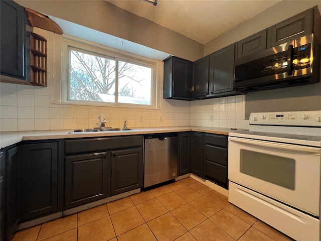 kitchen with tasteful backsplash, sink, light tile patterned floors, and appliances with stainless steel finishes