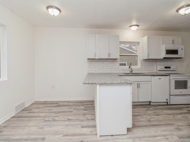 kitchen with white cabinets, light stone countertops, white appliances, and sink