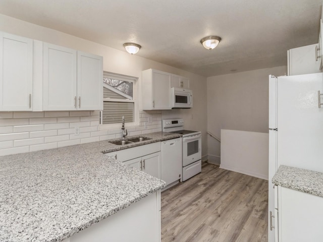 kitchen with light stone counters, sink, white cabinets, and white appliances