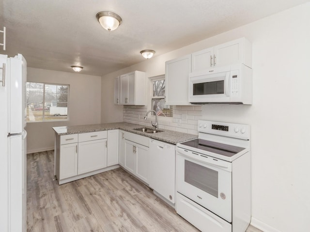 kitchen featuring white appliances, backsplash, sink, kitchen peninsula, and white cabinetry