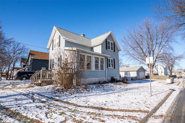 snow covered property with a garage and an outdoor structure