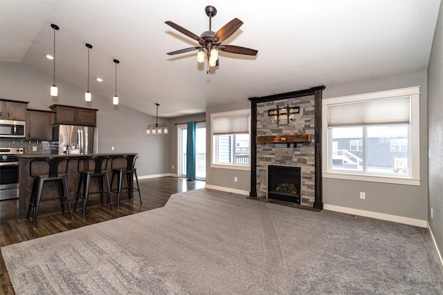 living room with ceiling fan, a fireplace, and vaulted ceiling