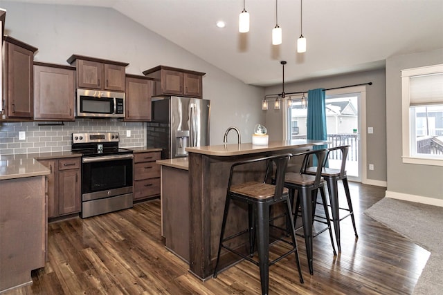 kitchen with a center island, hanging light fixtures, stainless steel appliances, tasteful backsplash, and lofted ceiling