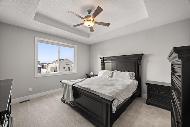 carpeted bedroom featuring a textured ceiling, a tray ceiling, and ceiling fan