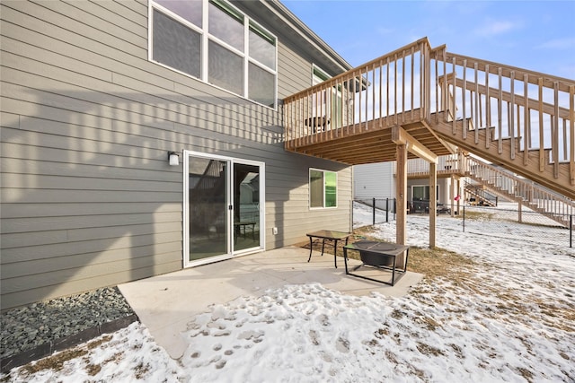 snow covered patio with a wooden deck