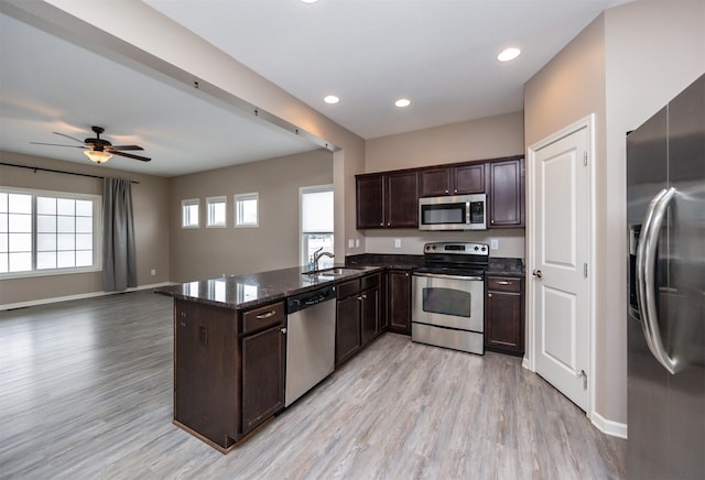 kitchen with kitchen peninsula, dark brown cabinetry, light hardwood / wood-style flooring, and appliances with stainless steel finishes