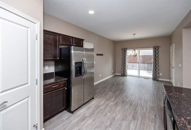 kitchen with pendant lighting, stainless steel fridge, dark stone countertops, dark brown cabinetry, and a chandelier