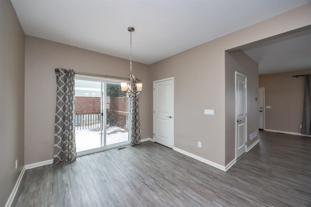 unfurnished dining area featuring dark hardwood / wood-style floors and an inviting chandelier