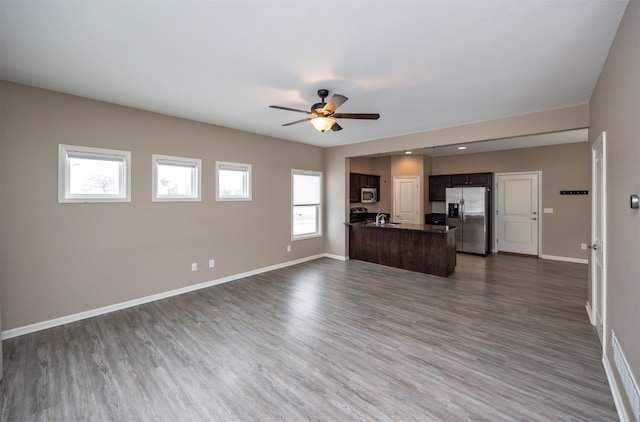 unfurnished living room featuring ceiling fan, dark hardwood / wood-style flooring, plenty of natural light, and sink