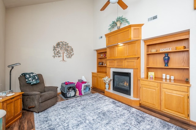 living room featuring a towering ceiling, dark hardwood / wood-style flooring, and ceiling fan