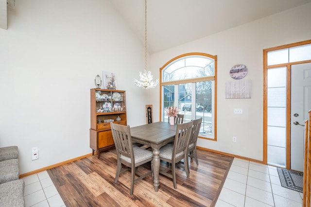 tiled dining room with lofted ceiling and an inviting chandelier