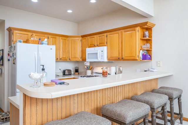 kitchen featuring a kitchen breakfast bar, white appliances, and kitchen peninsula