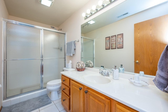 bathroom featuring tile patterned flooring, vanity, toilet, and a shower with shower door