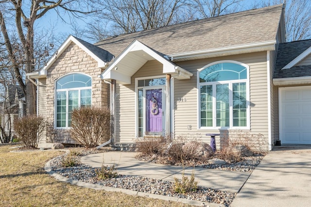 view of front facade featuring stone siding, an attached garage, driveway, and a shingled roof