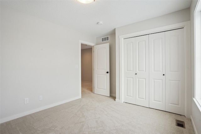 unfurnished bedroom featuring light colored carpet and a closet