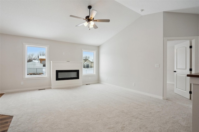 unfurnished living room featuring ceiling fan, plenty of natural light, light carpet, and lofted ceiling